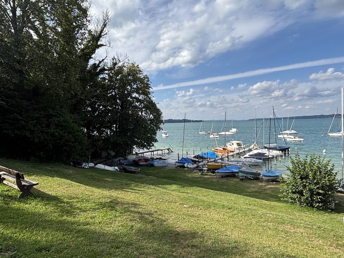 Uferwiese mit gelagerten Booten und Blick über den See