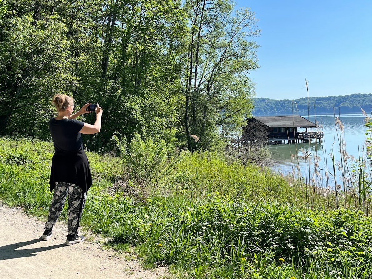 Spaziergängerin fotografiert ein Bootshaus am Starnberger See